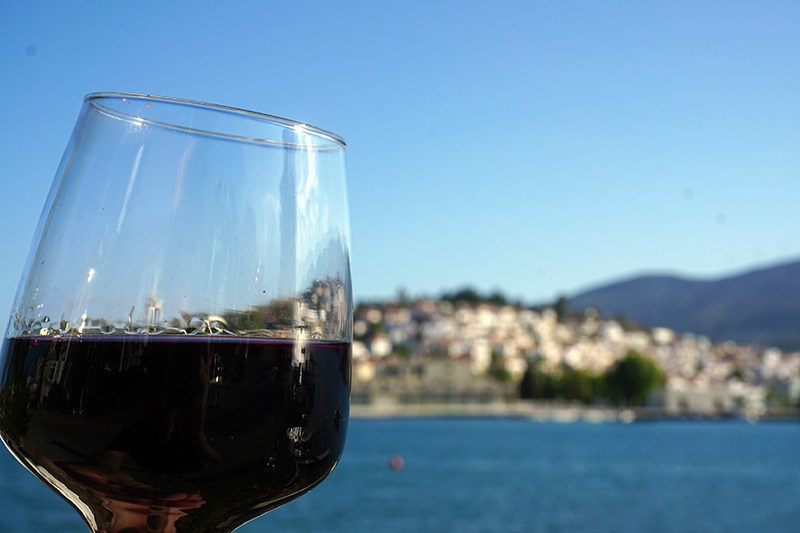 Ein Glas Rotwein, im Hintergrund Poros